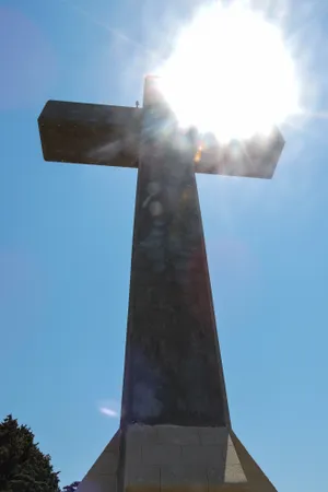 Cross-shaped turbine monument against sky background