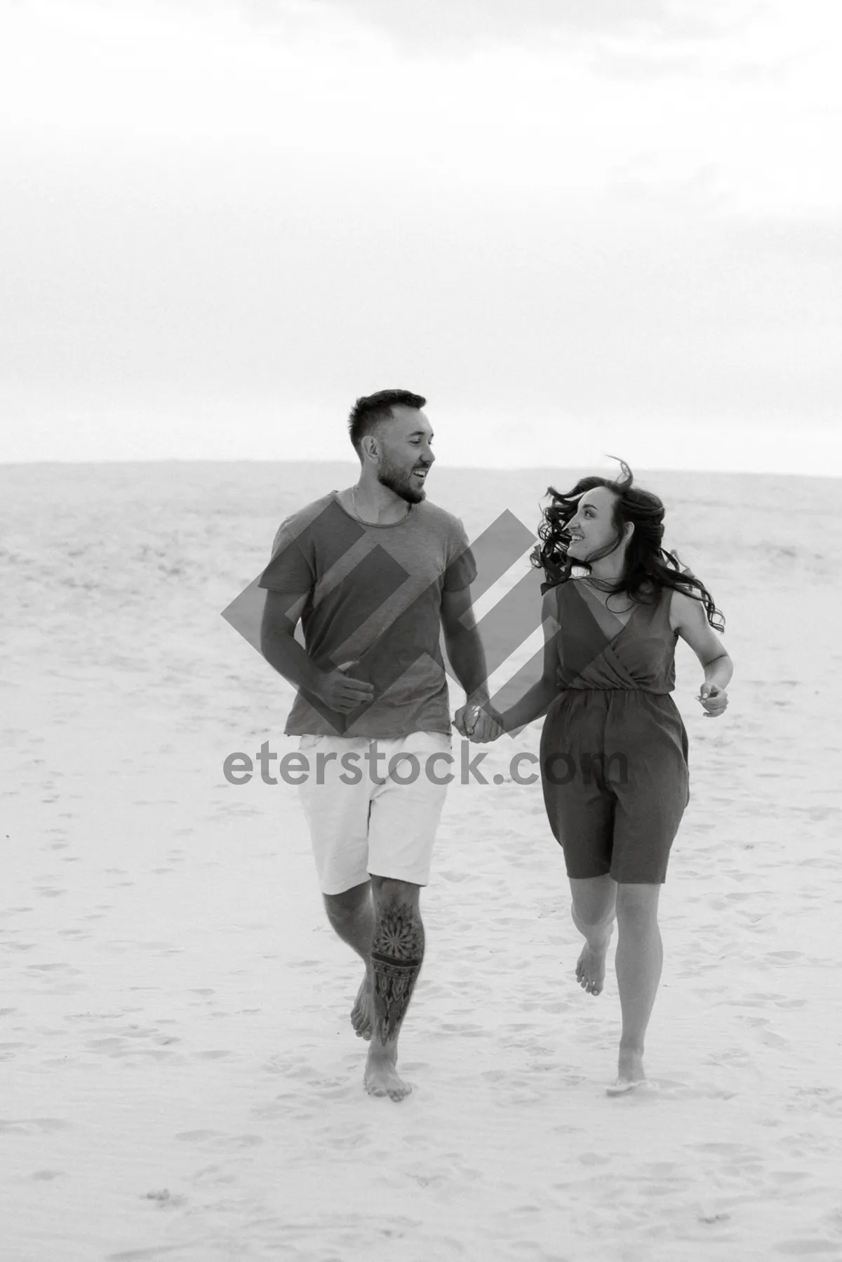 Picture of Happy couple walks along sandy beach at sunset