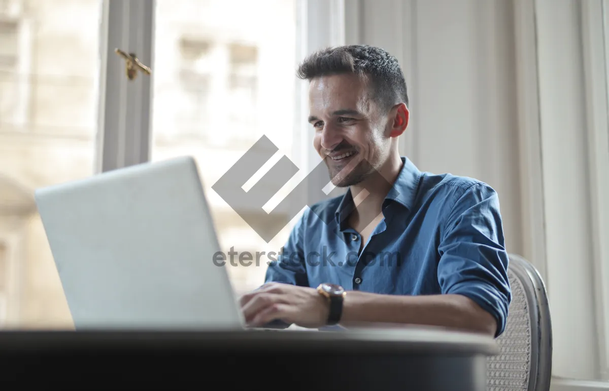 Picture of Happy male executive working on laptop in office