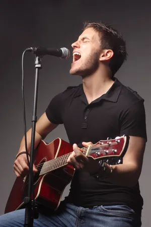 Attractive male rock singer with guitar on stage portrait