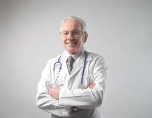 Confident elderly male doctor in medical uniform portrait.