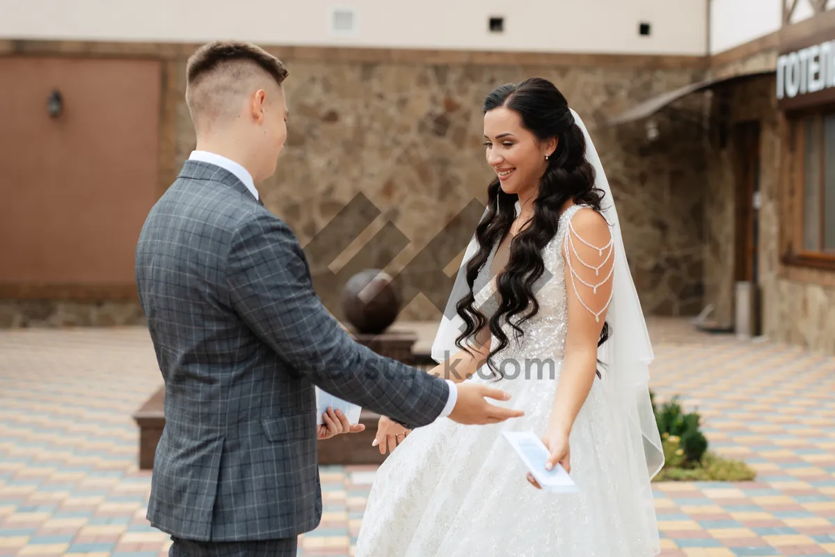 Picture of Happy couple in wedding attire holding bouquet.