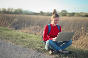 Happy boy with laptop in park on sunny day.