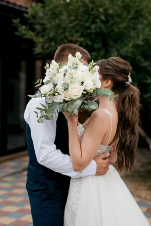 Smiling wedding couple outdoors with flower bouquet