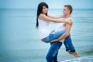 Happy couple running on beach at sunset