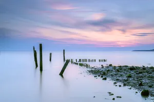 Beach silhouette at sunset over calm ocean.