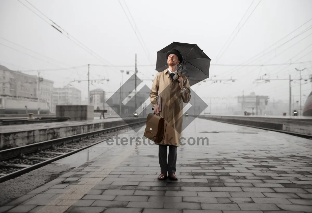 Picture of Man with umbrella walking on rainy city street