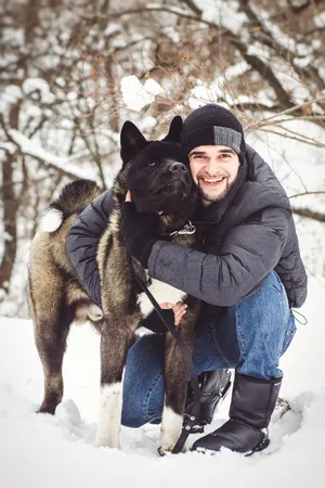 Active man snowshoeing with shepherd dog in snowy forest