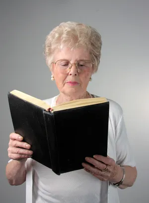 Happy elderly lady working on laptop at home office.