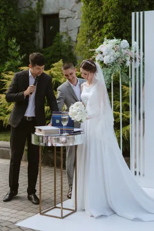 Happy wedding couple celebrating outdoors with a flower bouquet.