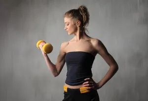 Happy person exercising with dumbbell and apple