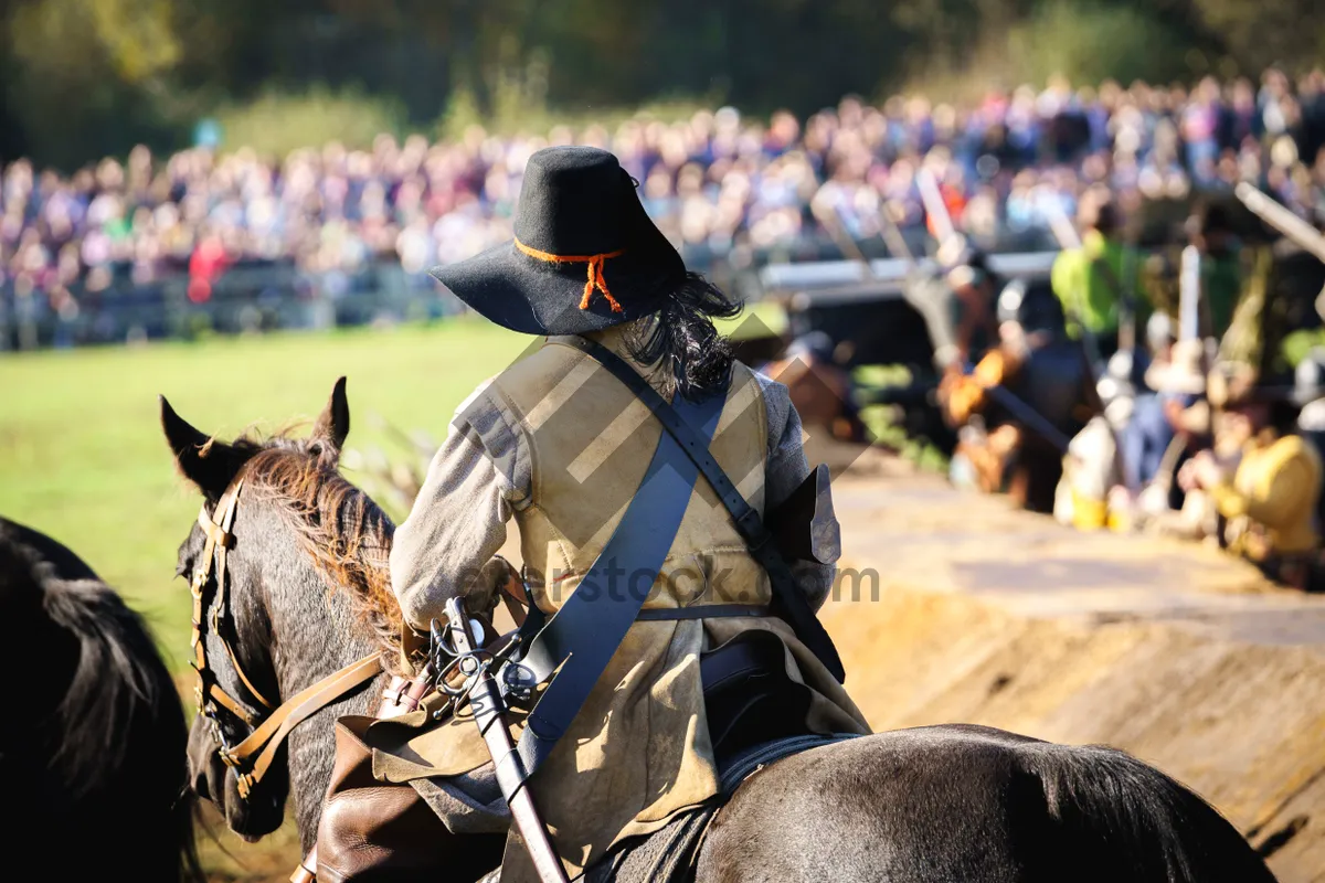 Picture of military horse trainer riding with gun outdoors