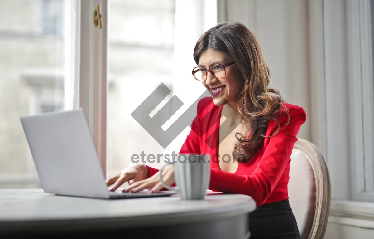 Picture of Smiling businesswoman working on laptop at home office