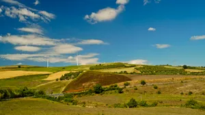 Scenic rural landscape with tree, mountain, and sun.