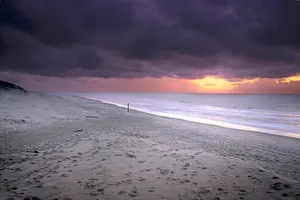 Tropical sunset over crystal blue waves on beach coast.