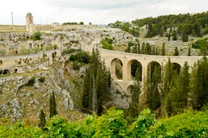 Old viaduct crossing river in forest landscape.