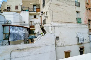 Old stone building with air conditioning unit on balcony.