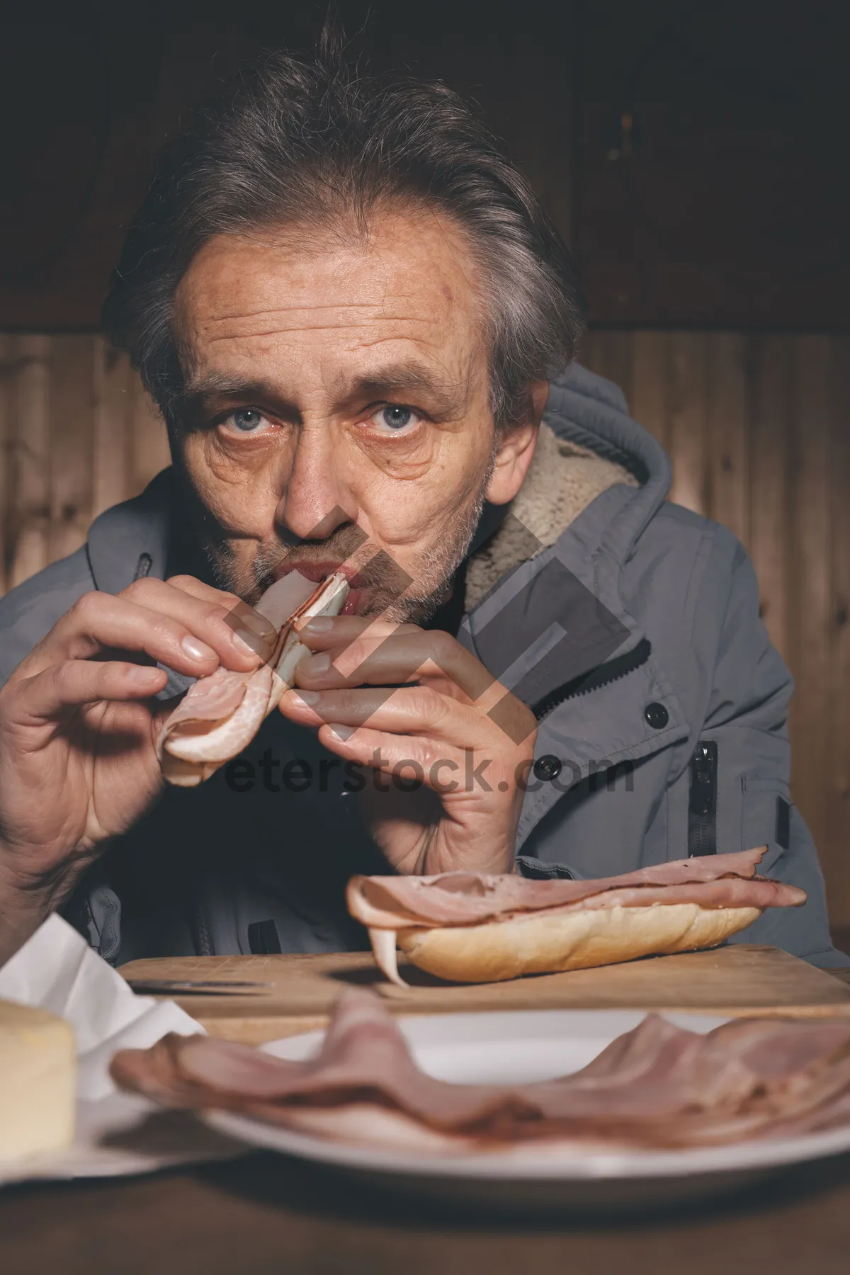 Picture of Senior man sitting at home with sandwich.