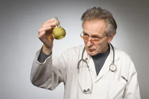 Smiling doctor holding stethoscope and apple.