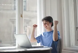 Happy male professional sitting with laptop in office.