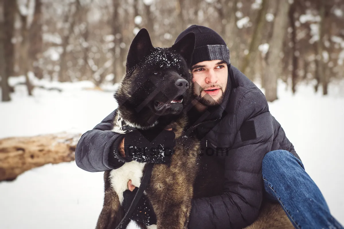 Picture of Smiling man playing with dog in snowy winter landscape