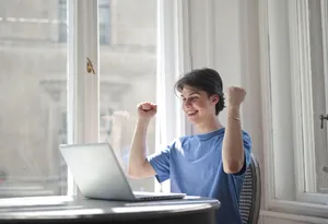 Happy male businessman working on laptop in office