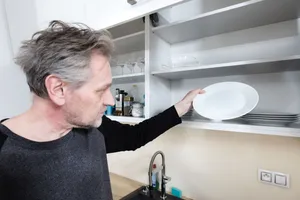 Smiling man working in office kitchen with fridge