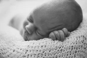 Sweet newborn baby boy peacefully sleeping on hospital bed.