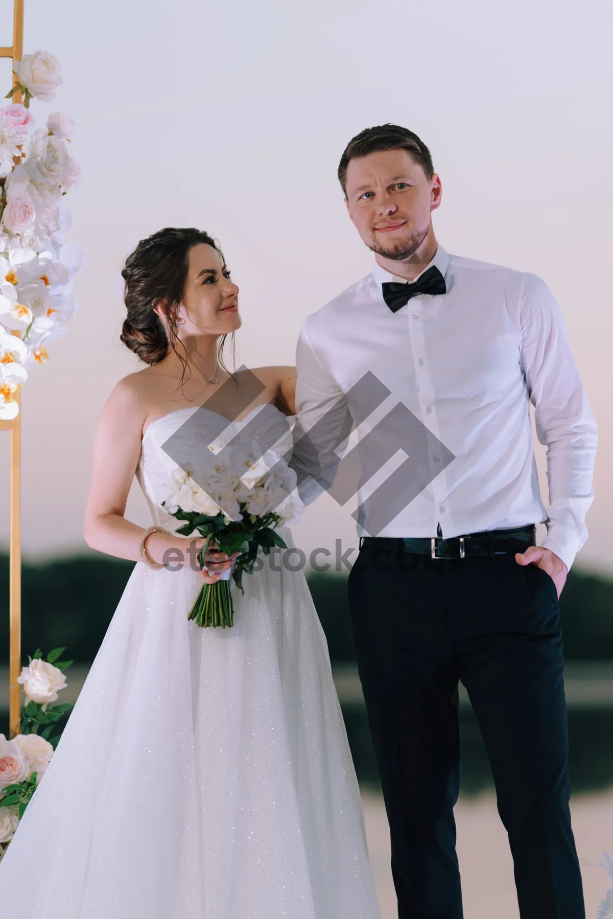 Picture of Happy Wedding Couple Smiling Outdoors with Flowers.