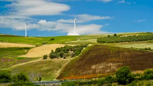 Rural landscape with wind turbine on grassy hill